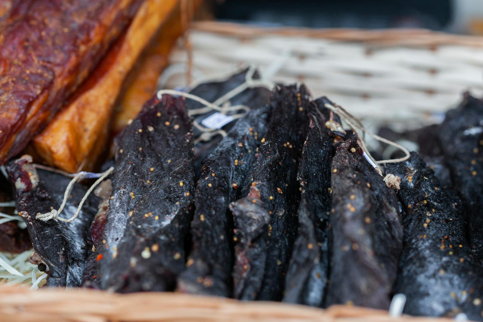 Close-up of spiced dried meat slices on a wooden cutting board