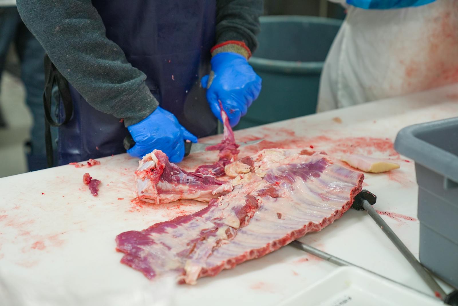 Butcher cutting fresh meat at the counter with a cleaver