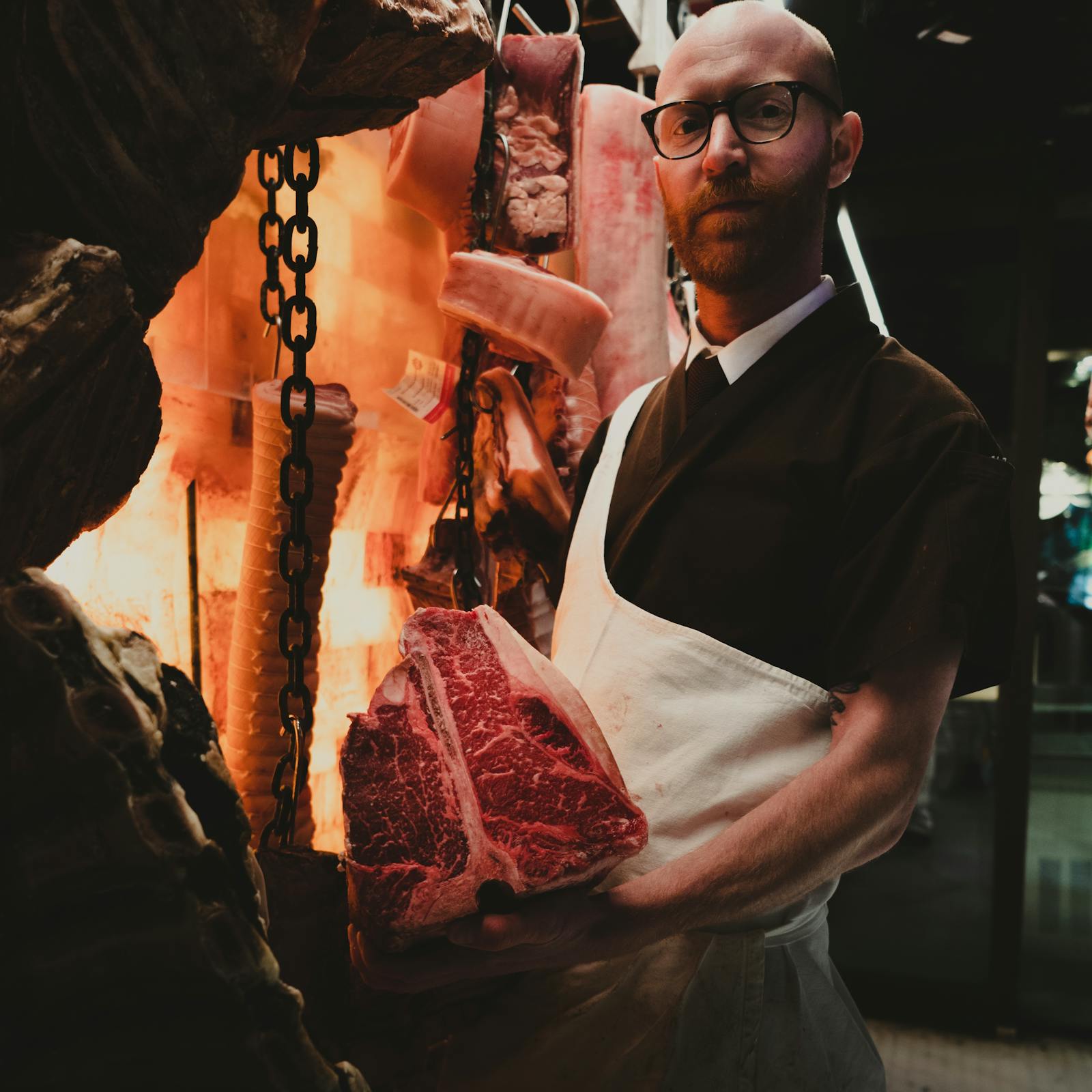 Smiling butcher in a white coat presenting a plate of fresh meat