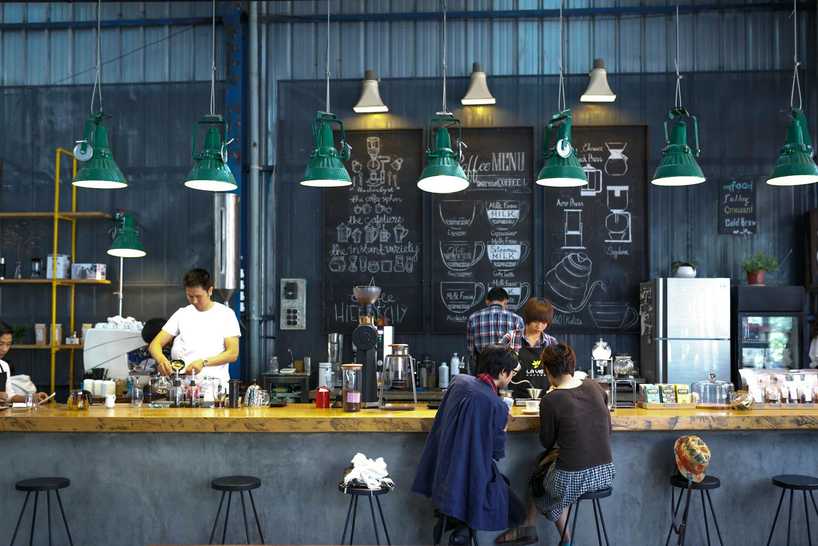 Friendly barista handing a cup of coffee to a customer in a cosy café