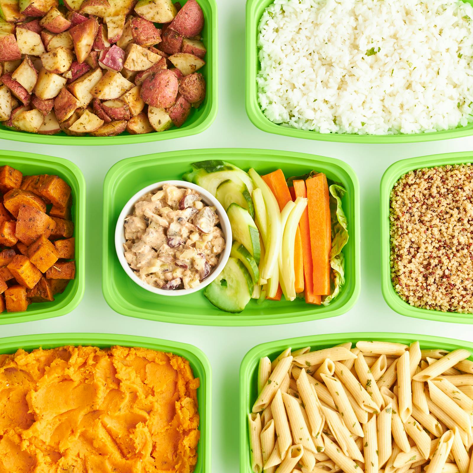 Colourful meal prep trays with pasta, broccoli, chicken and carrots